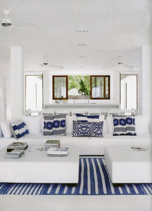 Sofá branco com tapete listrado azul e almofadas azuis 