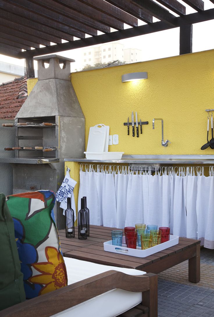 Área de lazer com churrasqueira simples com parede amarela e 