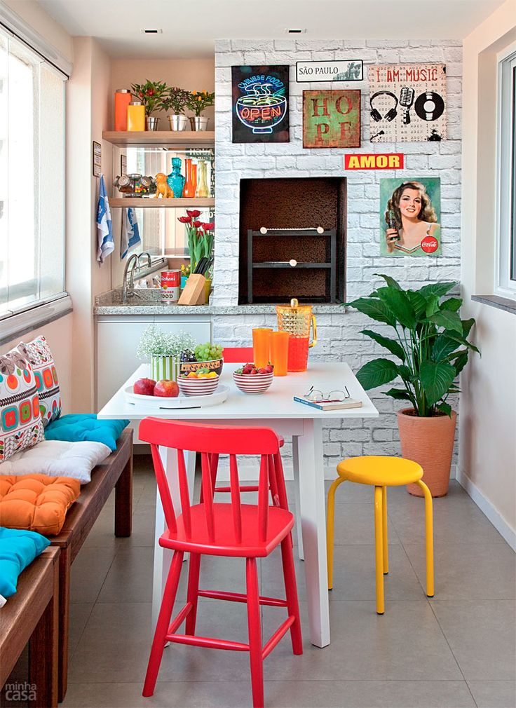 Área de lazer com churrasqueira em apartamento com bancos coloridos e quadros