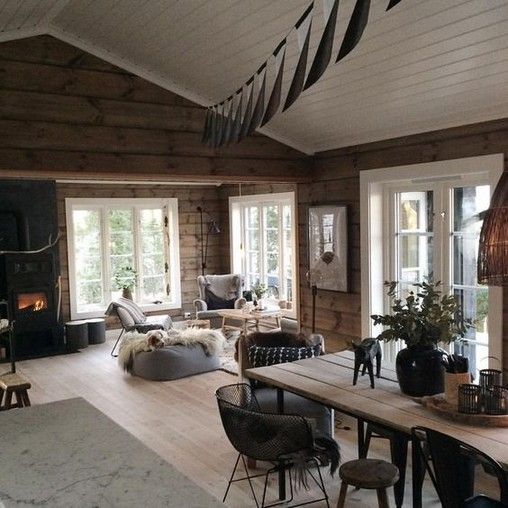 Casa de madeira com teto branco e paredes escuras, mesa de jantar e sala integradas