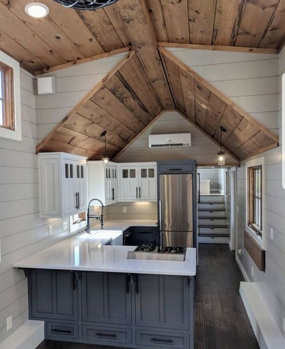 Casa de madeira com cozinha azul e bancada branca e armarios suspensos