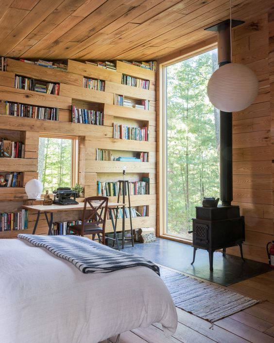 Quarto em casa de madeira com escrivaninha e prateleiras com livros
